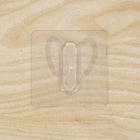 Close-up of transparent wall hook showing its adhesive pad