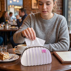 Handbag shaped tissue dispenser featuring pink bow