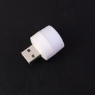 Mini portable yellow USB LED night light glowing beside a laptop keyboard